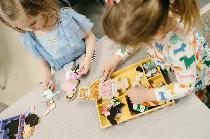 two little girls playing with paper dolls