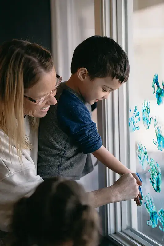 a kid putting hand prints on glass